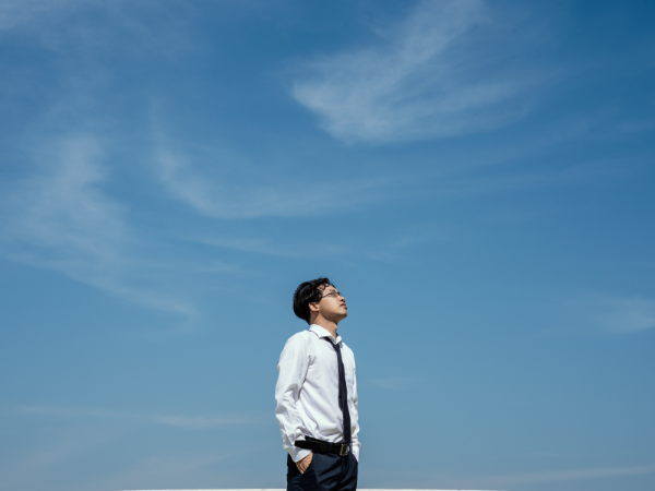 Dark haired male in suit starting up at blue sky
